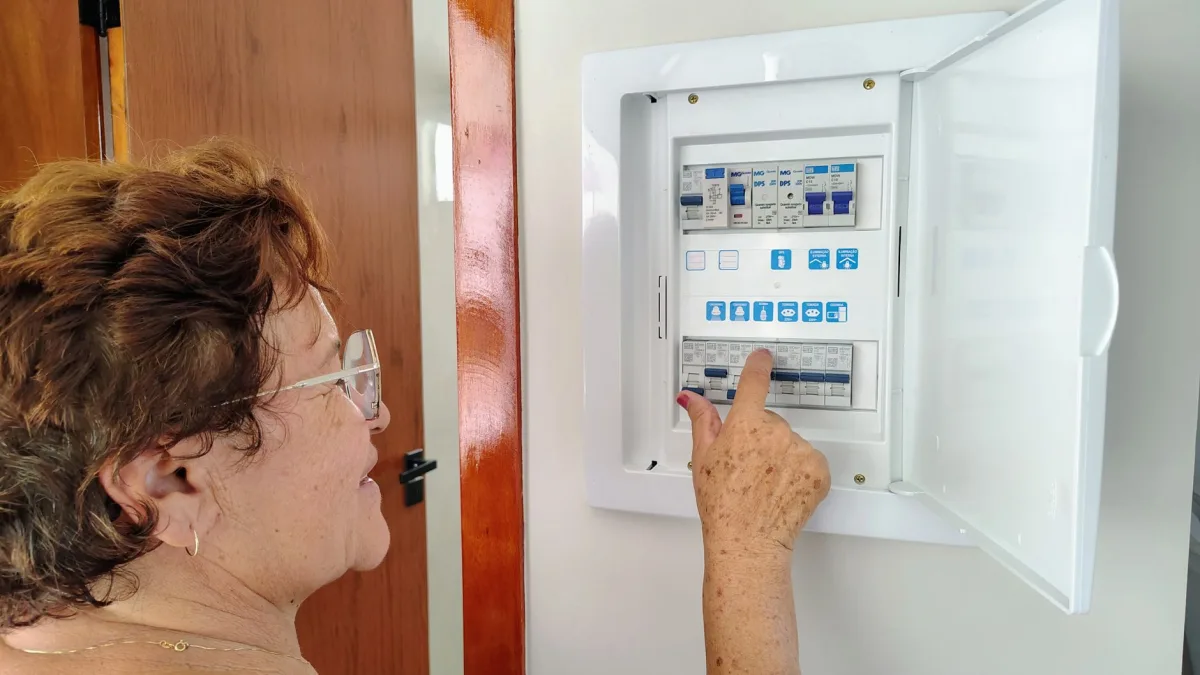 A senior woman is adjusting an fuse indoors, demonstrating home safety. A senior woman is adjusting an fuse indoors, demonstrating home safety.
